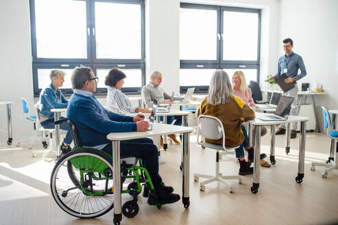 Eine Gruppe fröhlicher älterer Menschen, die einen Computer- und Technologiekurs besuchen. - HPIF16395
