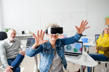 Eine Gruppe fröhlicher Senioren mit VR-Brillen im Computer- und Technologieunterricht. - HPIF16407