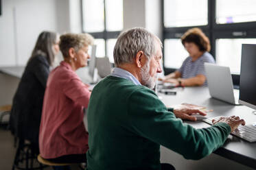 Gruppe älterer Menschen, die an einem Computer- und Technologiekurs teilnehmen und arbeiten. - HPIF16451