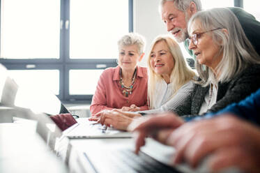 Eine Gruppe fröhlicher älterer Menschen, die einen Computer- und Technologiekurs besuchen. - HPIF16452