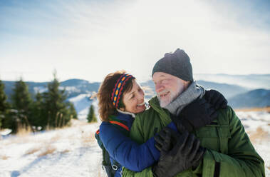 Front view portrait of senior couple hikers standing in snow-covered winter nature. - HPIF16503