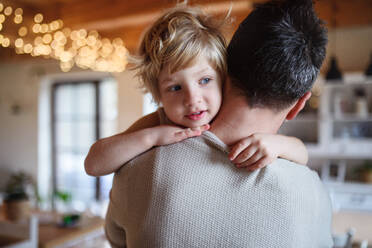 Rear view of father carrying small sick unhappy son indoors at home, comforting him. - HPIF16530