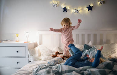 Two small laughing children jumping on bed indoors at home, having fun. - HPIF16550