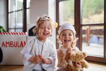 Zwei kleine Kinder in Arztkitteln, die zu Hause spielen und Spaß haben. - HPIF16566