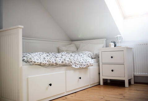Weißes Holzeinzelbett mit Nachttisch im Schlafzimmer zu Hause. - HPIF16573