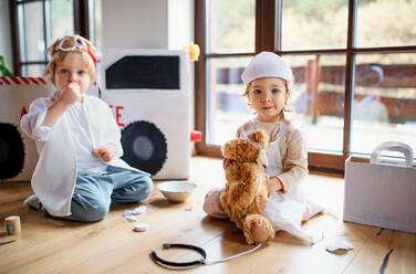 Two small children with doctor uniforms and stethoscope indoors at home, playing. - HPIF16582