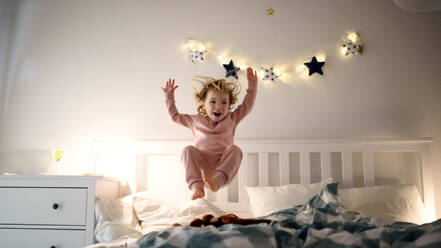 Zwei kleine lachende Kinder, die zu Hause auf dem Bett herumspringen und Spaß haben. - HPIF16585