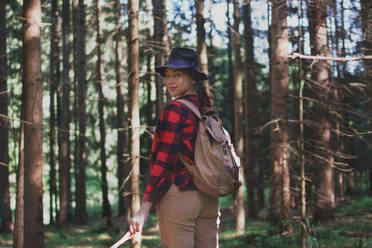 Junge Frau auf einem Spaziergang im Freien im Wald in der Sommernatur, zurückblickend. - HPIF16589