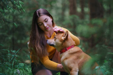 Glückliche junge Frau mit einem Hund auf einem Spaziergang im Freien in der sommerlichen Natur. - HPIF16618