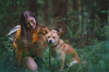 Glückliche junge Frau mit einem Hund auf einem Spaziergang im Freien in der sommerlichen Natur. - HPIF16620