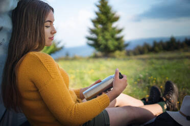 Seitenansicht einer jungen Frau im Freien auf einer Wiese in sommerlicher Natur, die sich ausruht. - HPIF16624