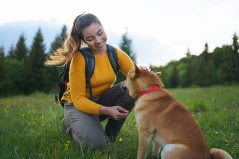 Glückliche junge Frau mit einem Hund auf einem Spaziergang im Freien in der sommerlichen Natur. - HPIF16628