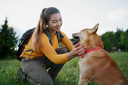 Glückliche junge Frau mit einem Hund auf einem Spaziergang im Freien in der sommerlichen Natur. - HPIF16629
