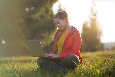 Side view of happy young woman using laptop in summer nature, outdoor office concept. - HPIF16630