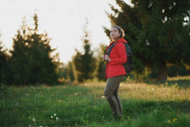 Seitenansicht einer jungen Frau auf einem Spaziergang im Freien auf einer Wiese in der Sommernatur, Wandern. - HPIF16639