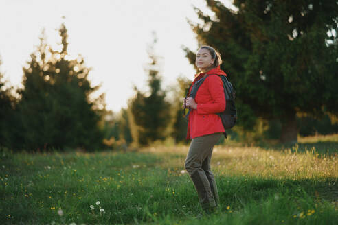 Side view of young woman on a walk outdoors on meadow in summer nature, walking. - HPIF16639
