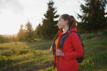 Seitenansicht einer jungen Frau auf einem Spaziergang im Freien auf einer Wiese in der Sommernatur, Wandern. - HPIF16641