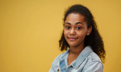 Porträt eines jungen Teenagers in einem Studio auf gelbem Hintergrund, der in die Kamera schaut. - HPIF16738