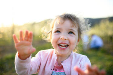 Vorderansicht eines kleinen Mädchens, das im Frühling im Obstgarten steht und Spaß hat. - HPIF16756