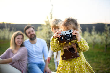 Eine Familie mit zwei kleinen Kindern sitzt im Frühling in der Natur und macht Fotos. - HPIF16767