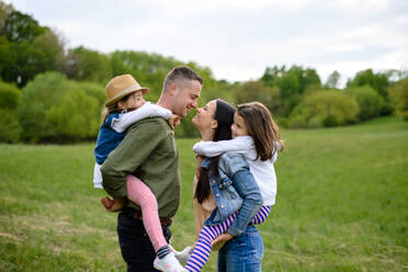 Happy family with two small daughters standing outdoors in spring nature, having fun. - HPIF16784