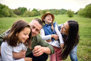 Front view of happy family with two small daughters having fun outdoors in spring nature. - HPIF16788