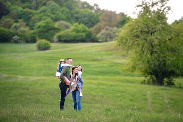 Glückliche Familie mit zwei kleinen Töchtern, die im Frühling in der Natur stehen, Totale. - HPIF16790