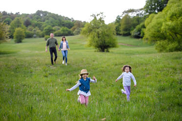 Glückliche Familie mit zwei kleinen Töchtern, die im Frühling draußen in der Natur herumlaufen und Spaß haben. - HPIF16791