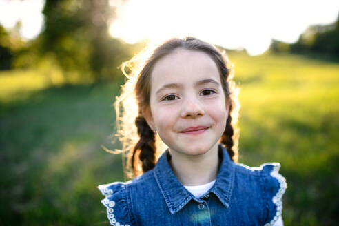 Porträt eines kleinen Mädchens, das im Freien in der Natur steht und in die Kamera schaut. - HPIF16808