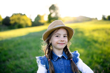 Front view portrait of small girl standing outdoors in spring nature, looking at camera. - HPIF16810