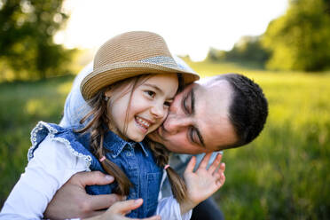 Front view of father playing with small daughter outdoors in spring nature, having fun. - HPIF16817