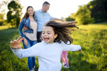 Glückliche Familie mit zwei kleinen Töchtern, die sich im Frühling in der Natur vergnügen und laufen. - HPIF16818
