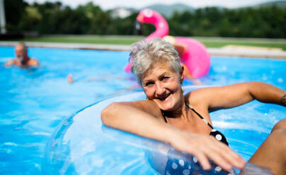 Porträt einer älteren Frau im Schwimmbad im Garten, die in die Kamera blickt, Kopierraum. - HPIF16857