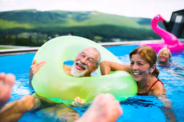 Eine Gruppe fröhlicher Senioren im Schwimmbad im Hinterhof, die Spaß haben. - HPIF16862