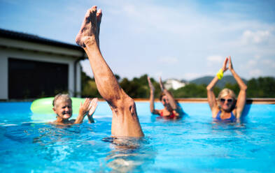 Group of cheerful seniors in swimming pool outdoors in backyard, having fun. - HPIF16868