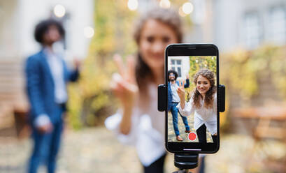 Porträt eines jungen Paares, das draußen auf der Straße ein Video mit dem Smartphone aufnimmt, Konzept für soziale Medien. - HPIF16873