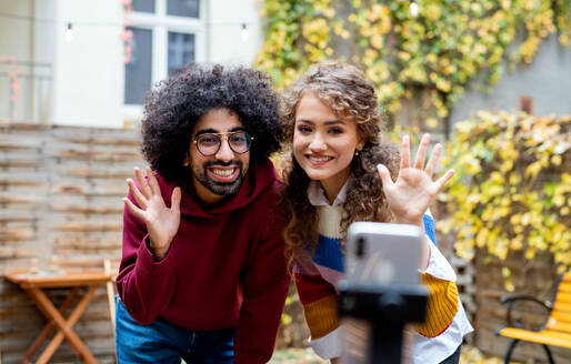 Porträt eines jungen Paares mit Smartphone, das draußen auf der Straße ein Video für soziale Medien dreht. - HPIF16875