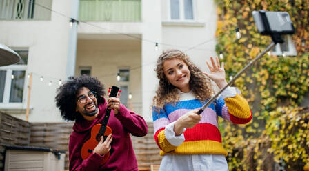 Porträt eines jungen Paares mit Smartphone, das draußen auf der Straße ein Video für soziale Medien dreht. - HPIF16877