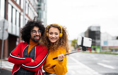 Porträt eines jungen Paares mit Smartphone, das draußen auf der Straße ein Video für soziale Medien dreht. - HPIF16888