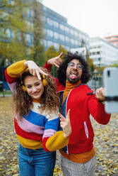 Porträt eines jungen Paares mit Smartphone, das draußen auf der Straße ein Video für soziale Medien dreht. - HPIF16896