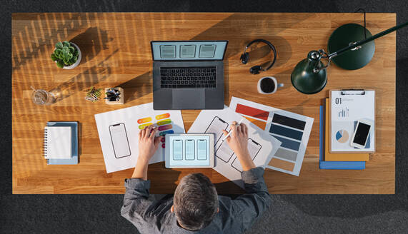 A top view of creative businessman working on laptop computer at desk with paperwork in home office. - HPIF16911