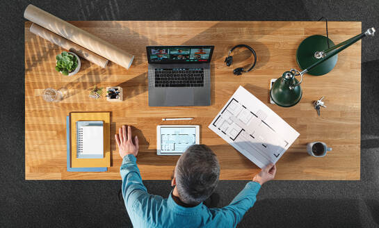 A top view of architect working on computer at desk with paperwork in home office, video call concept. - HPIF16914