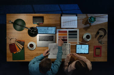 Draufsicht auf einen Architektenkollegen, der an einem Computer mit Papierkram im Home Office arbeitet. - HPIF16925