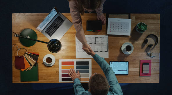 Eine Draufsicht von Architekten schütteln Hände am Schreibtisch mit Papierkram im Büro, Vorstellungsgespräch Konzept. - HPIF16930