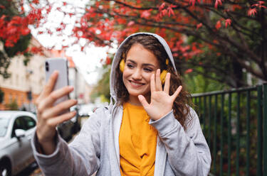 Portrait of young woman with smartphone outdoors on street, video for social media concept. - HPIF16934