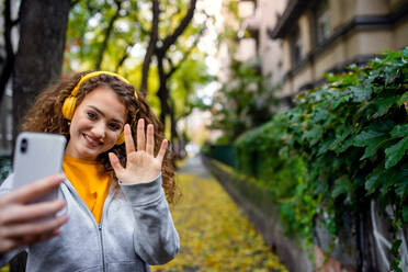 Porträt einer jungen Frau mit Smartphone im Freien auf der Straße, Video für Social-Media-Konzept. - HPIF16937