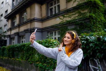 Portrait of young woman with smartphone outdoors on street, video for social media concept. - HPIF16938