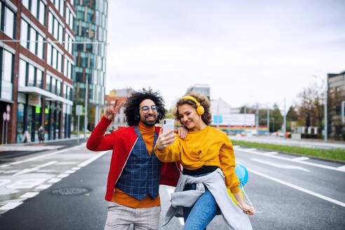 Porträt eines jungen Paares mit Smartphone, das draußen auf der Straße ein Video für soziale Medien dreht. - HPIF16941