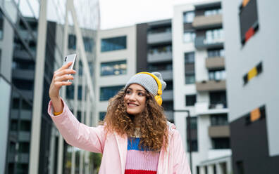 Porträt einer jungen Frau mit Smartphone, die draußen auf der Straße ein Video für soziale Medien dreht. - HPIF16951