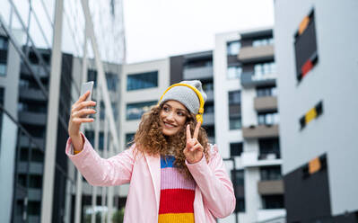 Porträt einer jungen Frau mit Smartphone, die draußen auf der Straße ein Video für soziale Medien dreht. - HPIF16952